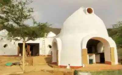 Superadobe earth construction with white domes and arches
