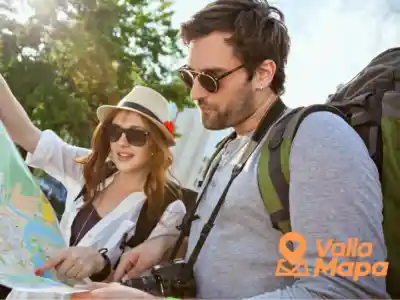 Two travelers with backpacks and sunglasses reading a paper map outdoors